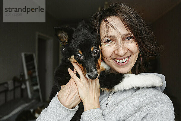 Lächelnde Frau mit Hund zu Hause