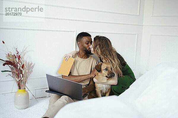 Couple kissing near dog at home