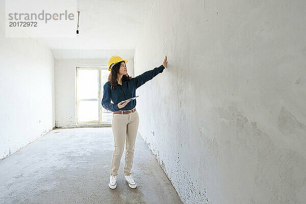 Architekt hält Tablet-PC in der Hand und untersucht Wand vor Ort