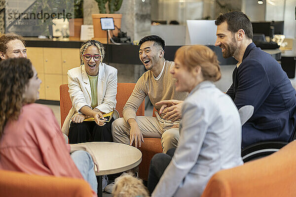 Fröhliche  vielfältige Kollegen  die bei Besprechungen am Arbeitsplatz über Strategien diskutieren