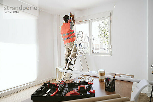 Reifer Techniker  der zu Hause am Fenster arbeitet