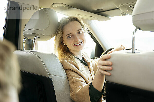 Schöne Frau mit blonden Haaren sitzt auf dem Fahrersitz im Auto