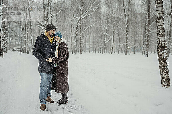 Älteres Paar steht im Schnee im Park