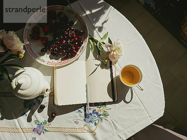 Tagebuch neben Teekanne und Obst auf dem heimischen Tisch