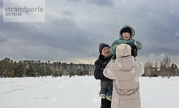 Großeltern spielen mit Enkel auf Schneefeld
