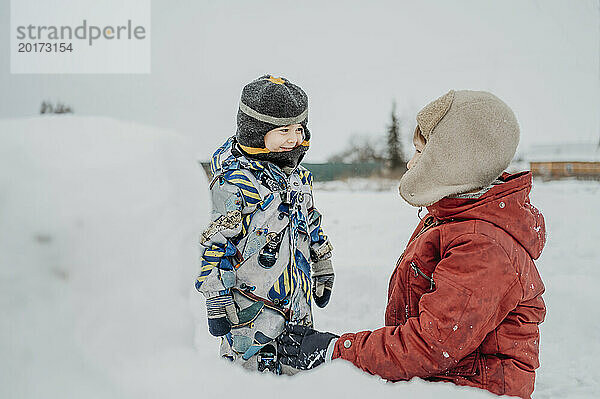 Siblings wearing warm clothes and playing in snow