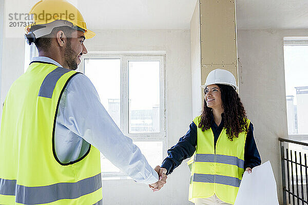 Lächelnder Architekt schüttelt seinem Kollegen vor Ort die Hand