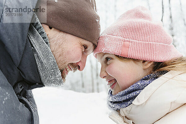 Verspielter Vater und Tochter haben Spaß im Winterwald
