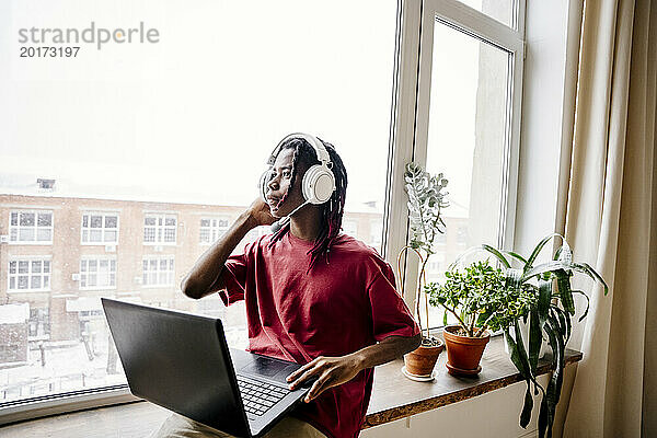 Mann trägt Headset und sitzt zu Hause mit Laptop