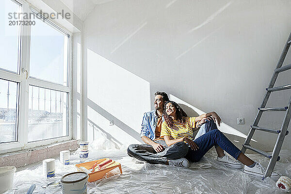 Glückliches Paar sitzt auf dem Boden im neuen Zuhause