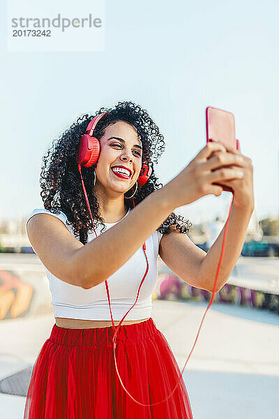 Glückliche Frau  die Musik hört und im Skatepark ein Selfie mit dem Smartphone macht