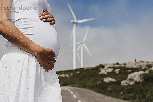 Spain  Madrid  Midsection of pregnant woman standing in front of wind farm