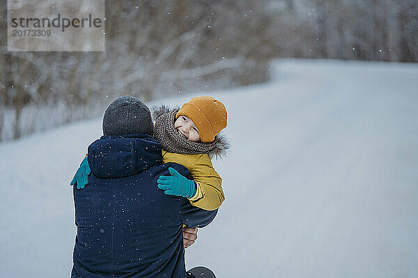 Mann umarmt Sohn im Winterwald