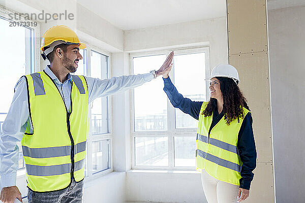 Smiling architects giving high five at site