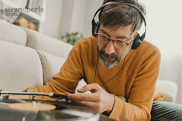 Mann hört Musik und stellt die Nadel auf einer altmodischen Schallplatte ein