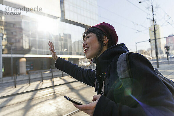 Lächelnde Frau mit Smartphone  die Fahrt auf der Straße ankündigt