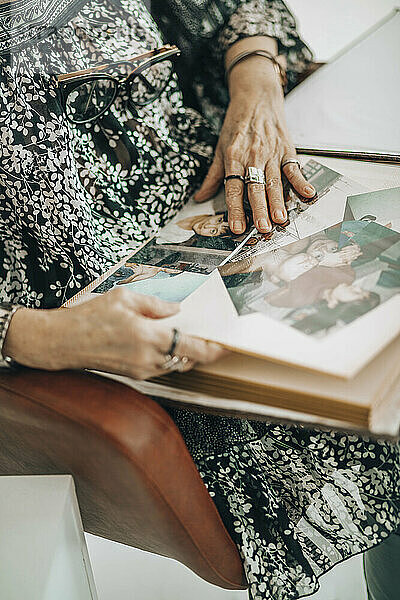 Ältere Frau sitzt zu Hause auf einem Stuhl mit Fotoalbum