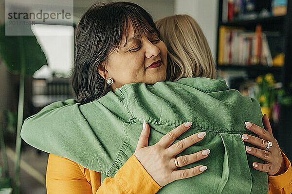 Smiling woman embracing daughter at home