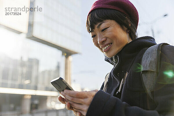 Lächelnde reife Frau  die an einem sonnigen Tag ihr Smartphone benutzt