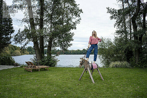 Frau steht auf Holzpferd vor See