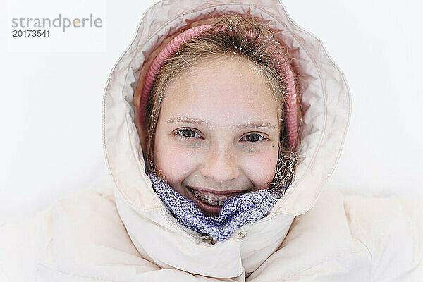 Lächelndes Mädchen in warmer Kleidung im Schnee