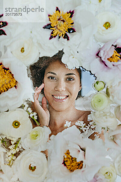 Lächelnde Frau liegt unter einer Glasoberfläche mit Blumen