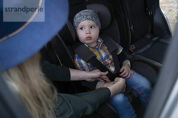 Mutter schnallt Sohn im Auto an