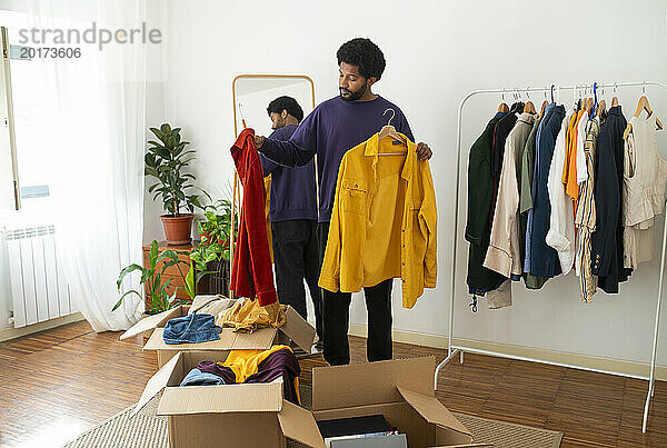 Junger Mann organisiert und entrümpelt Kleidung zu Hause