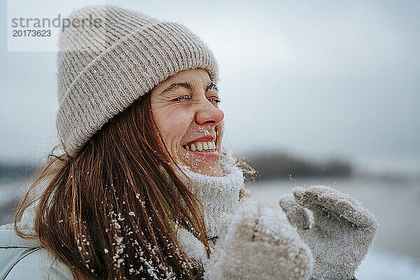 Glückliche Frau  die im Winter mit geschlossenen Augen lacht