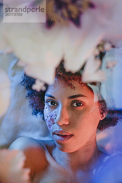 Young woman lying behind glass surface under neon lights