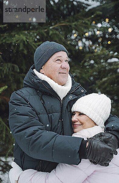 Reifer Mann umarmt Frau im Winterurlaub