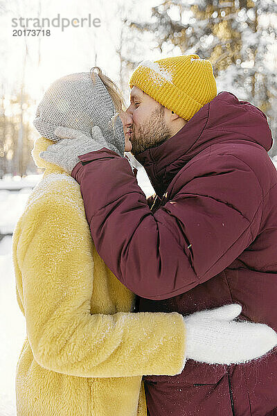 Mann küsst Frau im Winter an einem sonnigen Tag