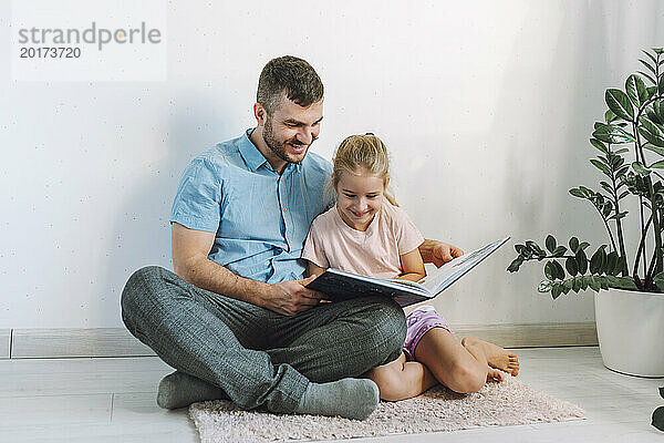 Glücklicher Vater und Tochter  die zu Hause ein Buch lesen