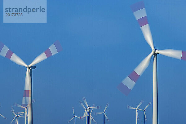 Wind farm turbines spinning against blue sky
