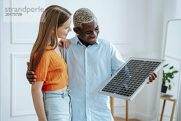 Glückliches Paar mit Solarpanel  das zu Hause steht