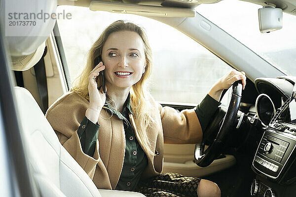 Schöne Frau  die im Auto sitzt und auf einem Smartphone spricht
