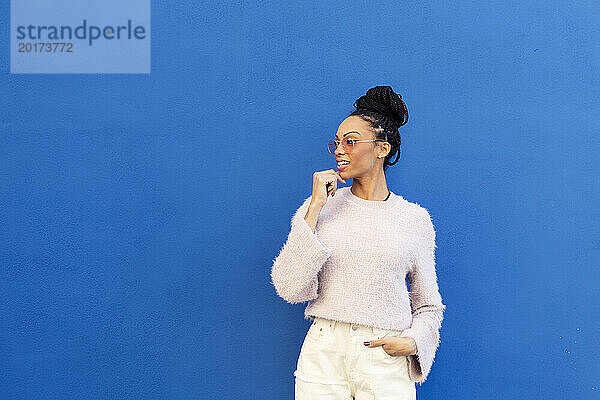 Lächelnde Frau steht vor blauer Wand