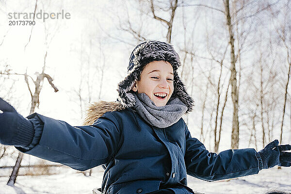 Cheerful boy with arms outstretched having fun in winter