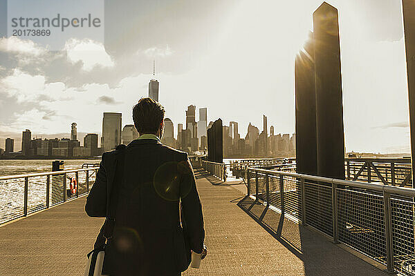Geschäftsmann läuft bei Sonnenuntergang in der Stadt auf einer Brücke
