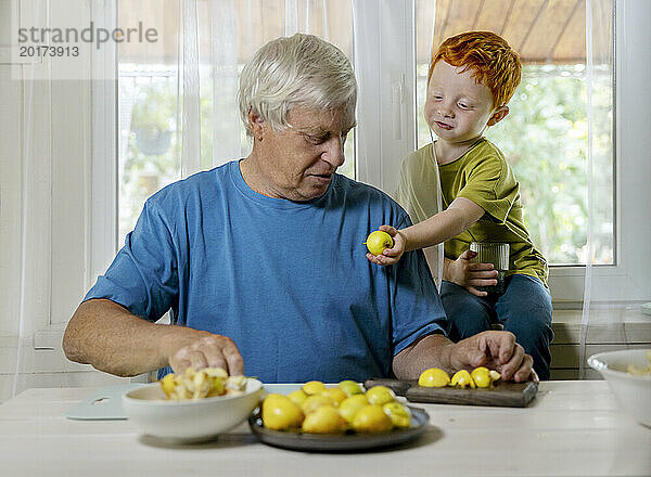 Junge reicht dem Großvater zu Hause Obst