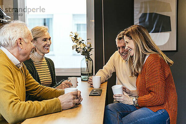 Fröhliche Freunde sitzen bei einer Kaffeetasse und genießen gemeinsam den Ruhestand
