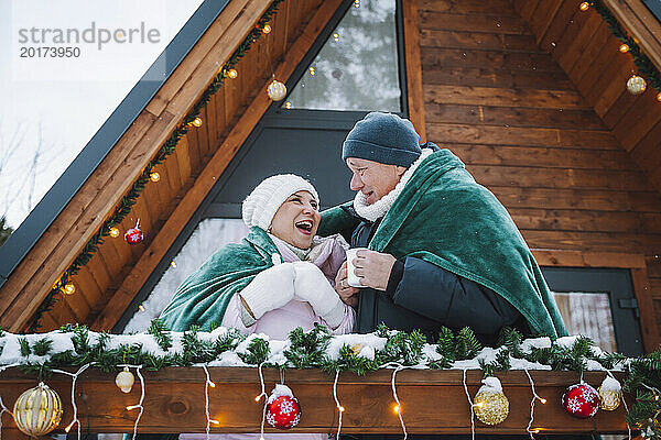 Glückliches Paar in Decke gehüllt vor Blockhütte