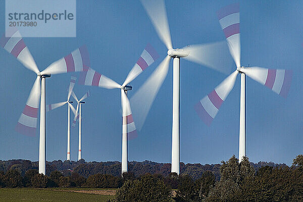 Spinning wind farm turbines in rural landscape