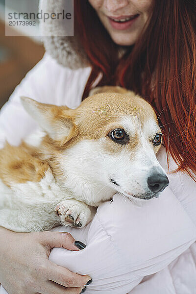 Junge Frau hält Corgi-Hund im Arm