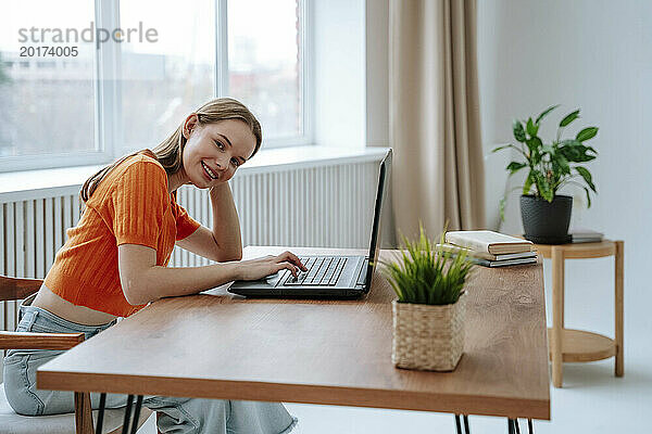 Lächelnder junger Freiberufler sitzt mit Laptop