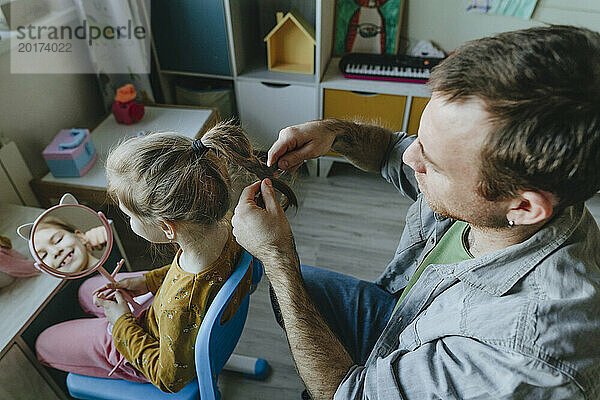 Vater flechtet seiner Tochter zu Hause die Haare