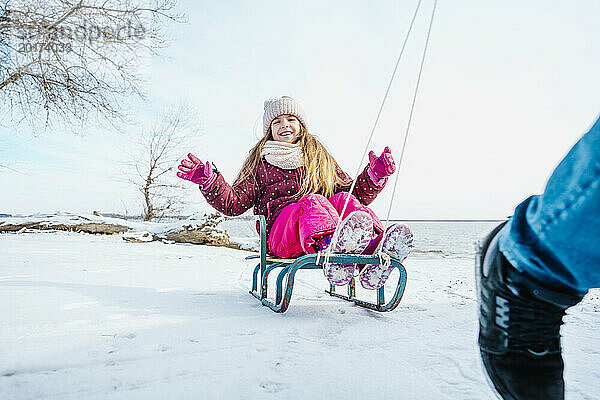 Lächelndes Mädchen sitzt im Winter auf Schlitten