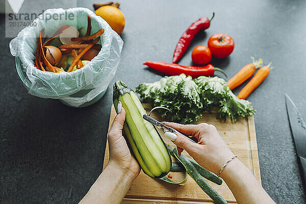 Hände einer Frau  die Zucchini auf der Küchentheke zu Hause schält