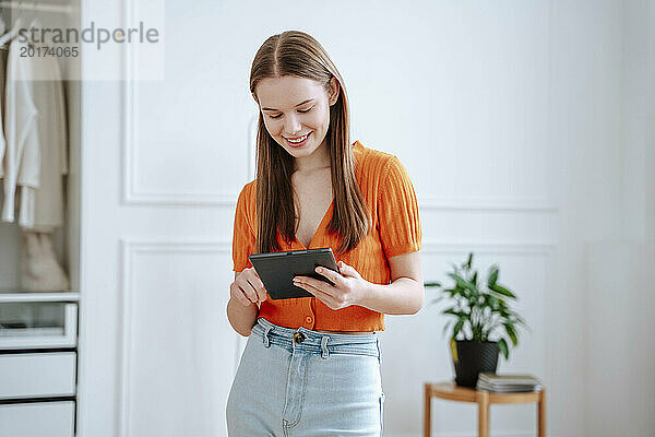 Glückliche junge Frau  die zu Hause einen Tablet-PC nutzt