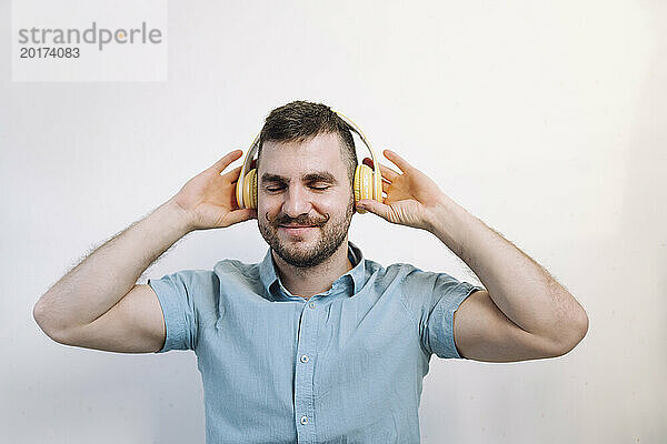 Glücklicher Mann  der Musik über drahtlose Kopfhörer hört